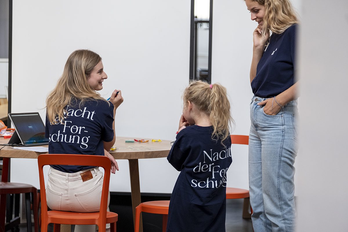Helferinnen und Kind in T-Shirts mit dem Nacht der Forschung Logo