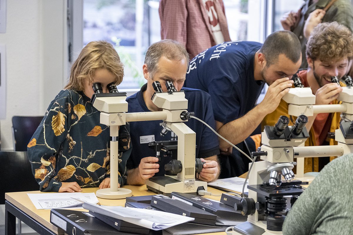 Besucherinnen und Besucher der NdF schauen in Mikroskope