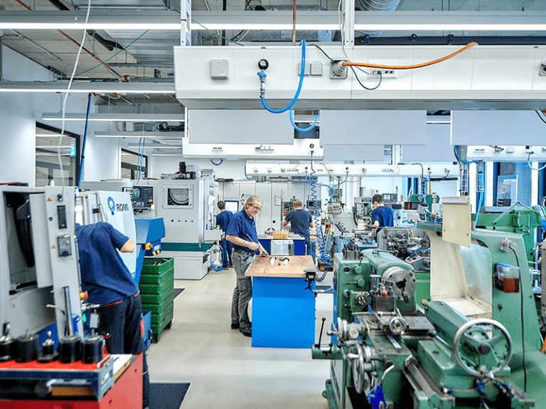 The technical workshop with 5 employees, all of whom are busy. many machines and tools can be seen.
