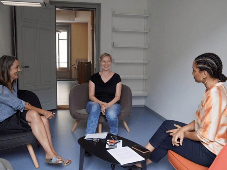 Drei Frauen, darunter Andrea Zimmermann, sitzen in einem Kreis. Sie sind in einem Gespräch.